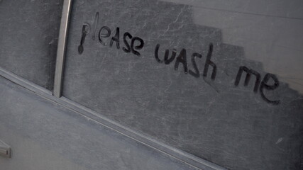 On a dirty car is written: "Please wash me." Prank over the owner of a black car.