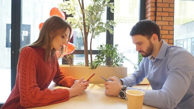 man and a woman in an argument are sitting at a table in a cafe with an offended expression on their faces.