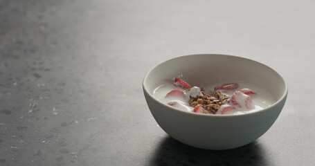 chocolate granola with strawberries and yogurt on a concrete countertop