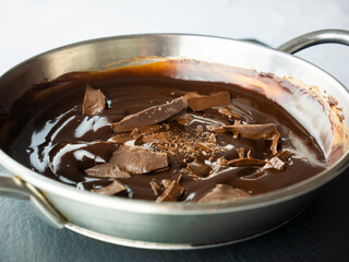 Temper the chocolate in a saucepan. Pieces of chocolate. Preparing cocoa mousse. Cooking sweets. Top view. Still life food.