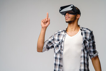 Young African-American young man wearing vr virtual reality headset over light grey background