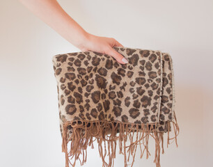  Warm autumn winter leopard scarf with fringe in the hands of a young woman. Large wide leopard print scarf
