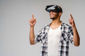 Young African-American young man wearing vr virtual reality headset over light grey background