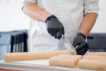 Chef hand in patisserie restaurant prepares cakes and decorates with chocolate icing