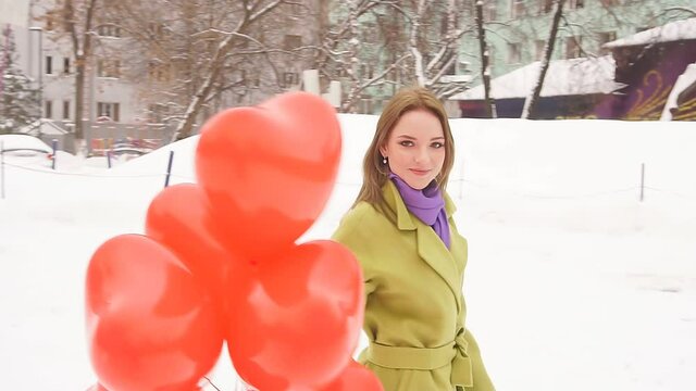 Slow-motion picture of a romantic young woman enjoying balloons. A woman spins with balloons in a Park on a winter day.