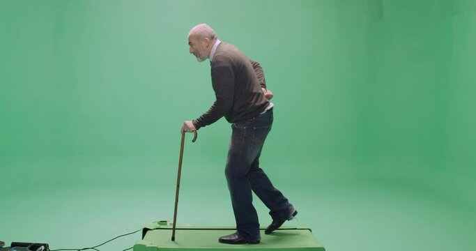 Studio, slow motion, green screen, a casually dressed senior man with a cane on a treadmill