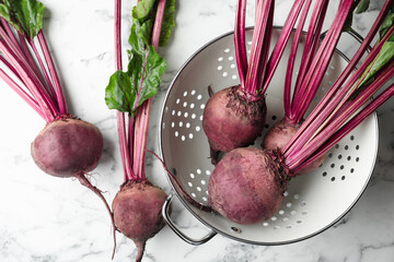 Raw ripe beets on white marble table, flat lay