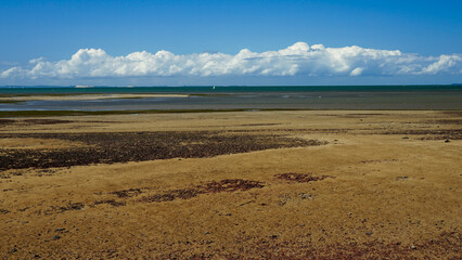 View across the sea to clouds on the horizon, at low tide