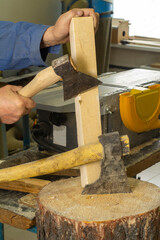 A gray-haired man in work clothes works with an axe. chops the log. carpenter's job. High quality photo