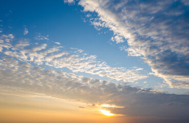 Naklejka na ściany i meble Cloudy sunset, long clouds covering the Sun