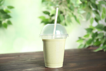 Tasty fresh milk shake in plastic cup on wooden table