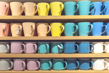 Many colorful cups stand in a row on the store shelf as a background.