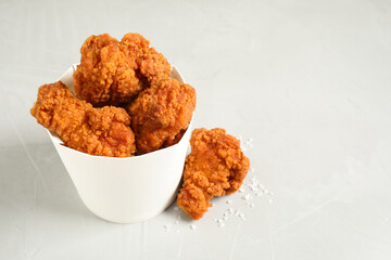 Tasty deep fried chicken pieces on white table. Space for text
