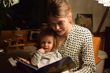 Fototapeta Mutter liest ihrer Tochter abends aus einem Buch vor. obraz