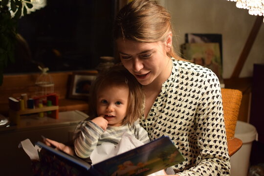 Mutter liest ihrer Tochter abends aus einem Buch vor.