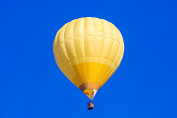 Yellow balloon with a basket for people on a background of blue sky.