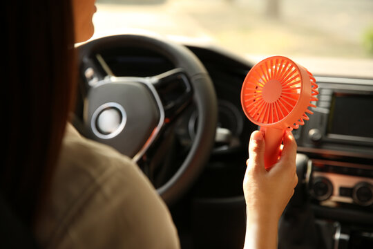 Woman With Portable Fan In Car On Hot Summer Day, Closeup