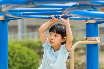 Fototapeta premium 真夏の公園で雲梯遊具を遊んでいる可愛い子供