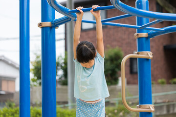 真夏の公園で雲梯遊具を遊んでいる可愛い子供