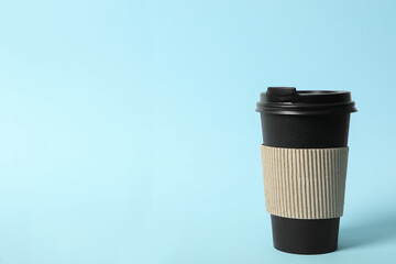 Takeaway paper coffee cup with cardboard sleeve on light blue background. Space for text
