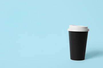 Takeaway paper coffee cup on light blue background. Space for text