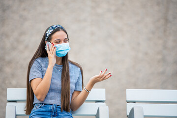Young woman wearing face mask is talking with cellphone