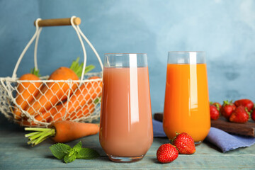 Glasses of delicious juices and fresh ingredients on blue wooden table