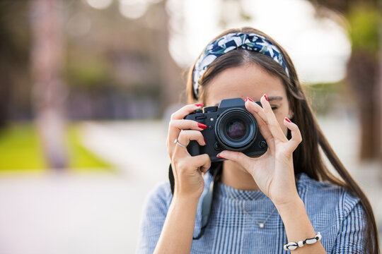 Portrait of a photographer covering her face with camera.