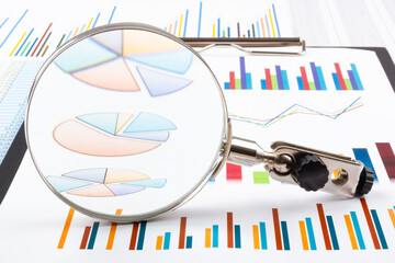 Magnifying glass lying on business charts and graphs. Business planning,accounting,analysis,financial planning and data Analysis concept