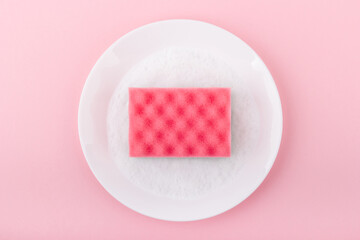 Pink sponge on the pink background. Top view. Cleaning and housewashing concept.