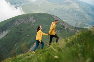 Fototapeta na wymiar Love in the mountains. Happy couple in love walking in the mountains holding hands and enjoying the beautiful scenery