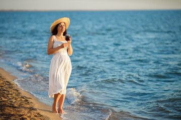 Fototapeta na wymiar woman holding glass of wine by the sea