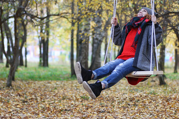 Young beautiful mother with her daughter on nature. A girl in a hat walks in the park. Girl in autumn city park in leaf fall.