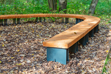 A recreation bench made of boards and wrought iron in a city park in autumn
