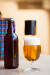 Frosty beer bottle and full glass of cold beer on the outdoor table.
