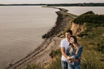 Fototapeta premium Romantic couple in embrance stand on the beach with mountains