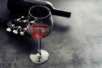 Guitar and high glass with red wine on a stone background.