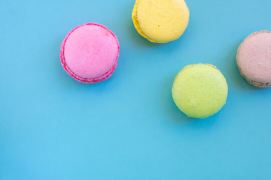 Group of biscuits known as macarons or macaroons on blue backgrouns. Round small sweet cookies.