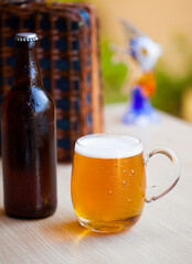 Frosty beer bottle and full glass of cold beer on the outdoor table.
