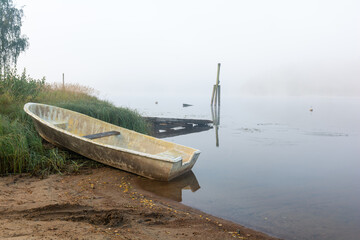 A boat by the lake shore with fog in the background