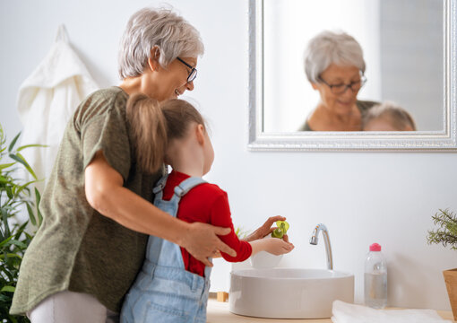 girl and her grandmother are washing hands