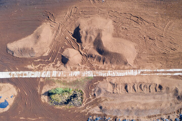 Aerial top down view of peat harvesting field with piles of peat. Peat extraction