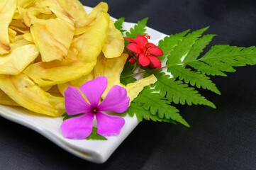 Fried durian with flowers and leaves in dish on table, Dark background