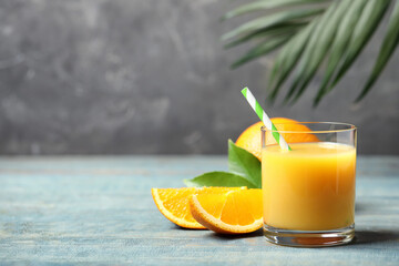 Fototapeta na wymiar Glass of orange juice and fresh fruits on wooden table. Space for text