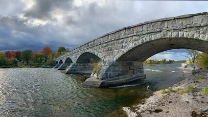 Fototapeta na wymiar Pakenham Bridge, a five arch stone bridge that crosses the Mississippi River on a stormy autumn day in Pakenham, Canada