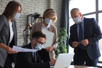Business people wearing protective face masks while holding a presentation on a meeting during coronavirus epidemic.