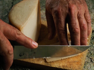 Hands of a man cutting an Idiazabal cheese