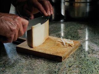 Hands of a man cutting an Idiazabal cheese