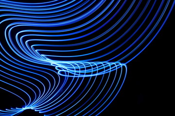 Long exposure photograph of neon blue colour in an abstract swirl, parallel lines pattern against a...