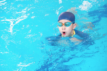 Fototapeta na wymiar Asia cute boy wearing swimming suit and goggles used foam to practice swimming in swimming pool. Healthy kid enjoying active lifestyle. Refreshing and relax to exercise on summer holiday